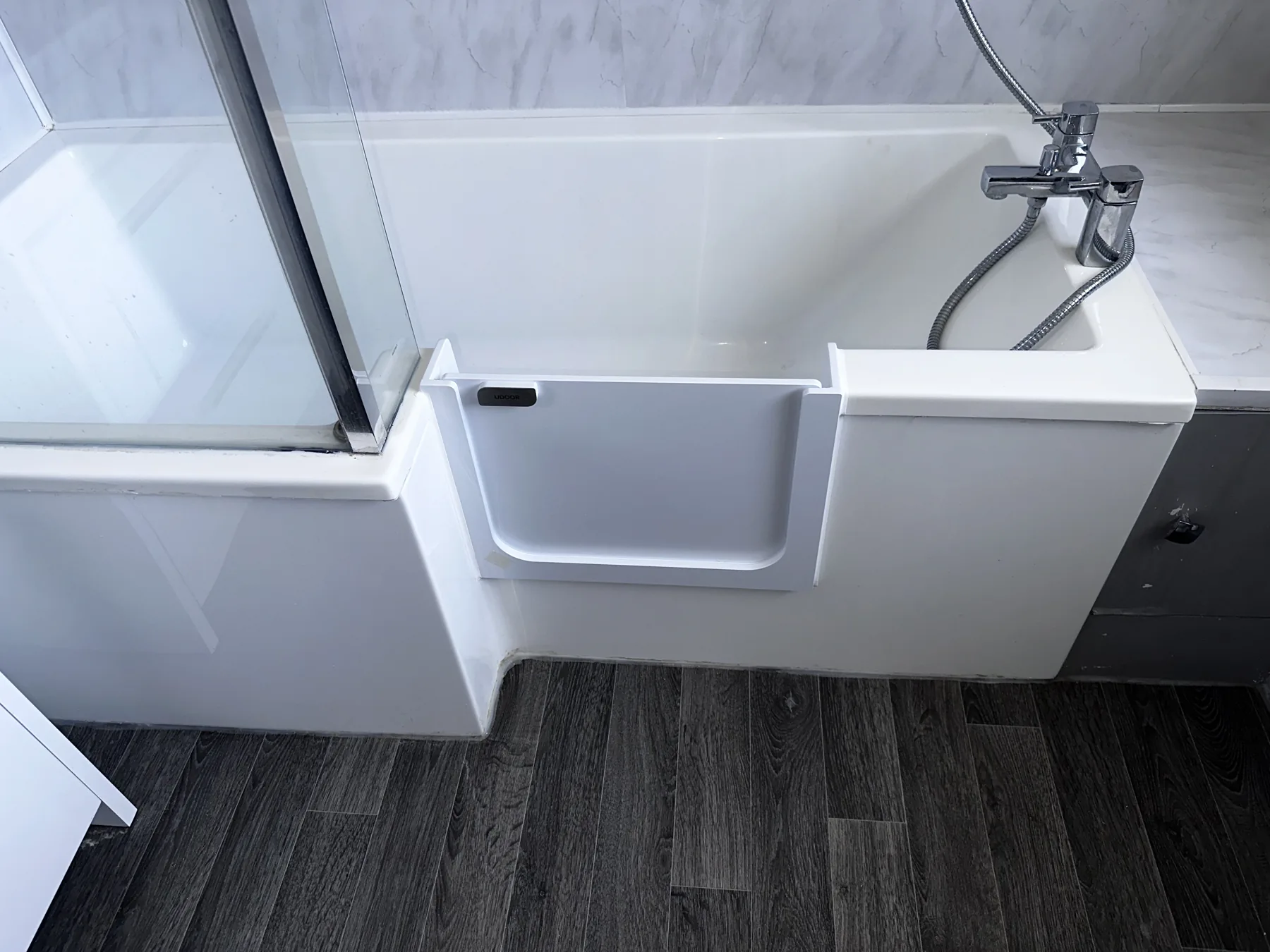 A UDOOR® door fitted into an L-shaped shower bath
